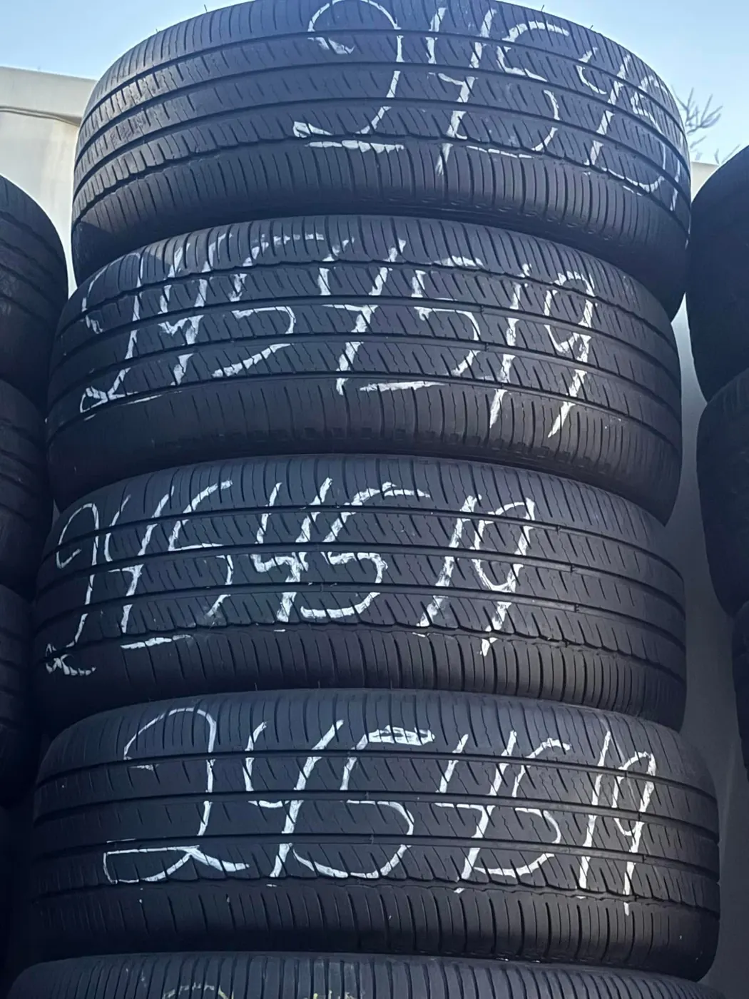 Stack of used tires with sizes written on the sidewalls